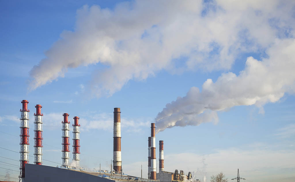 Industrial landscape. Power plant tubes with smoke above blue sk